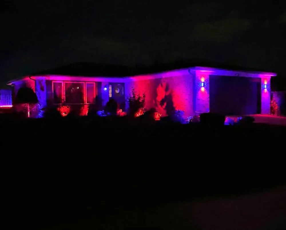 Home washed in deep red and violet permanent accent lighting after dark