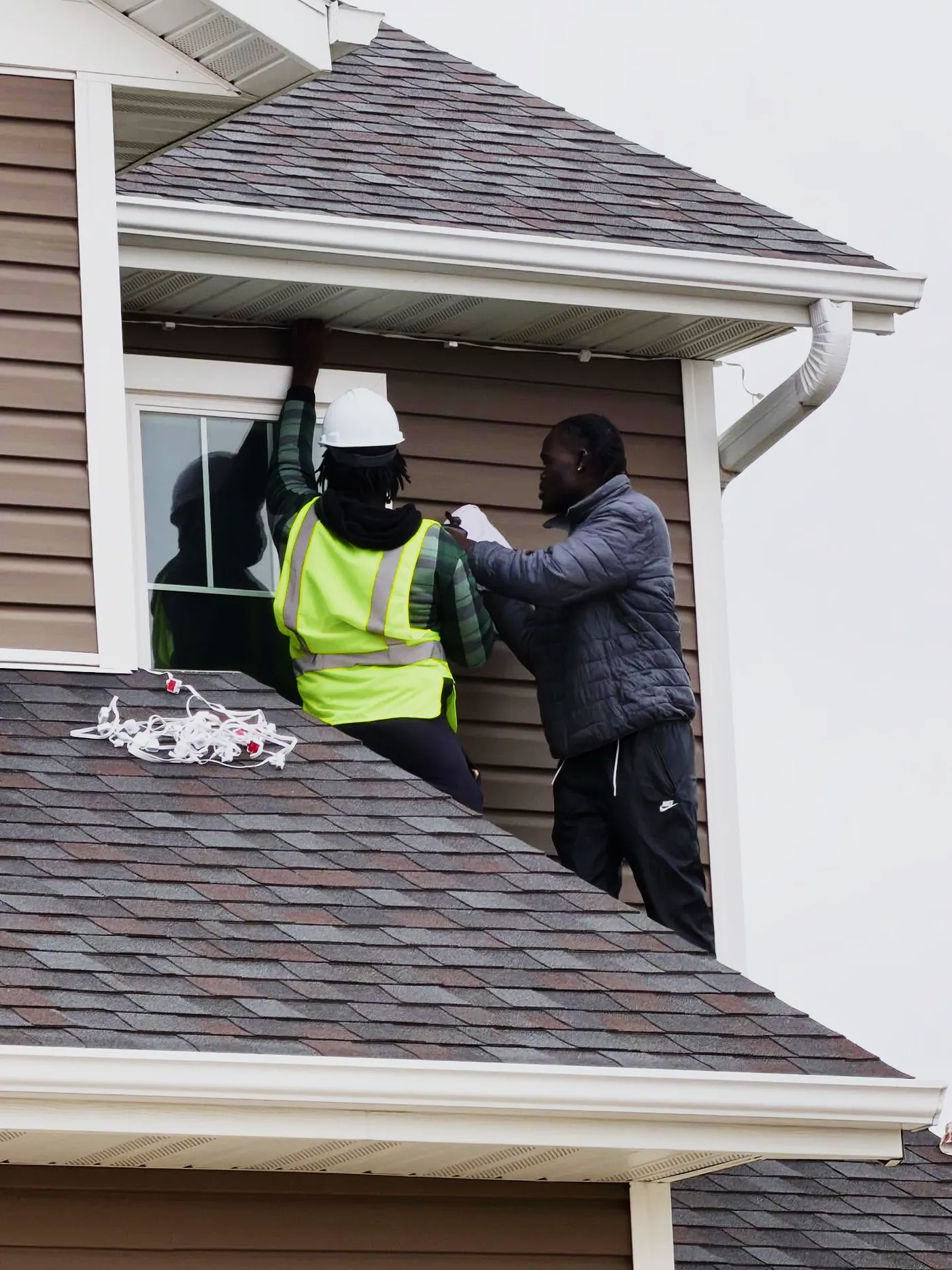 Two Maridadi crew members working carefully at the eaves of a Mankato home