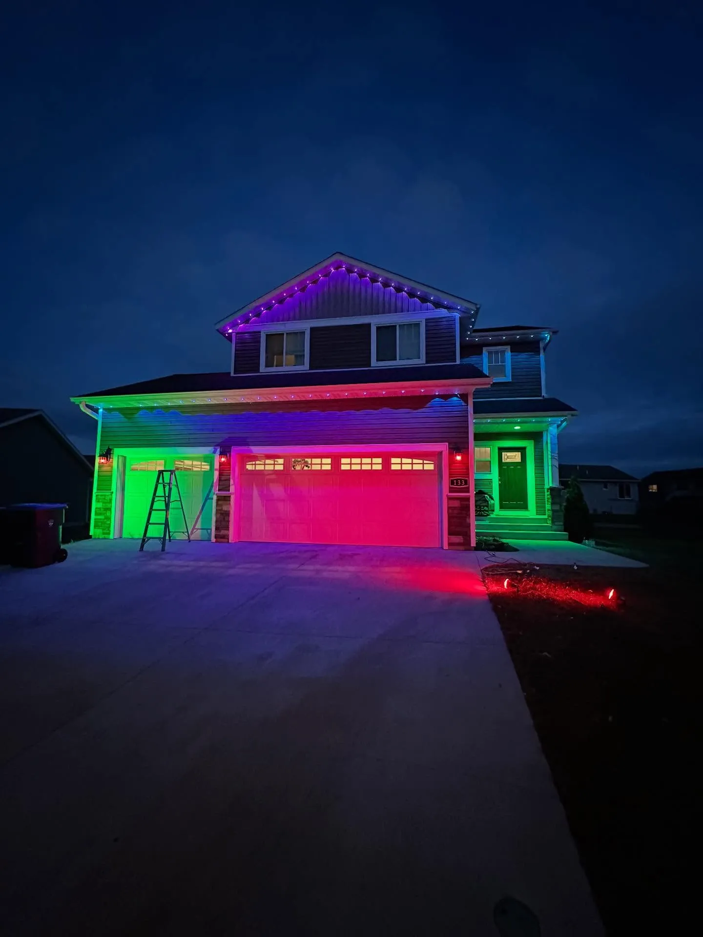 A Minnesota home glowing at dusk with Maridadi's permanent exterior lighting in green, red, and violet