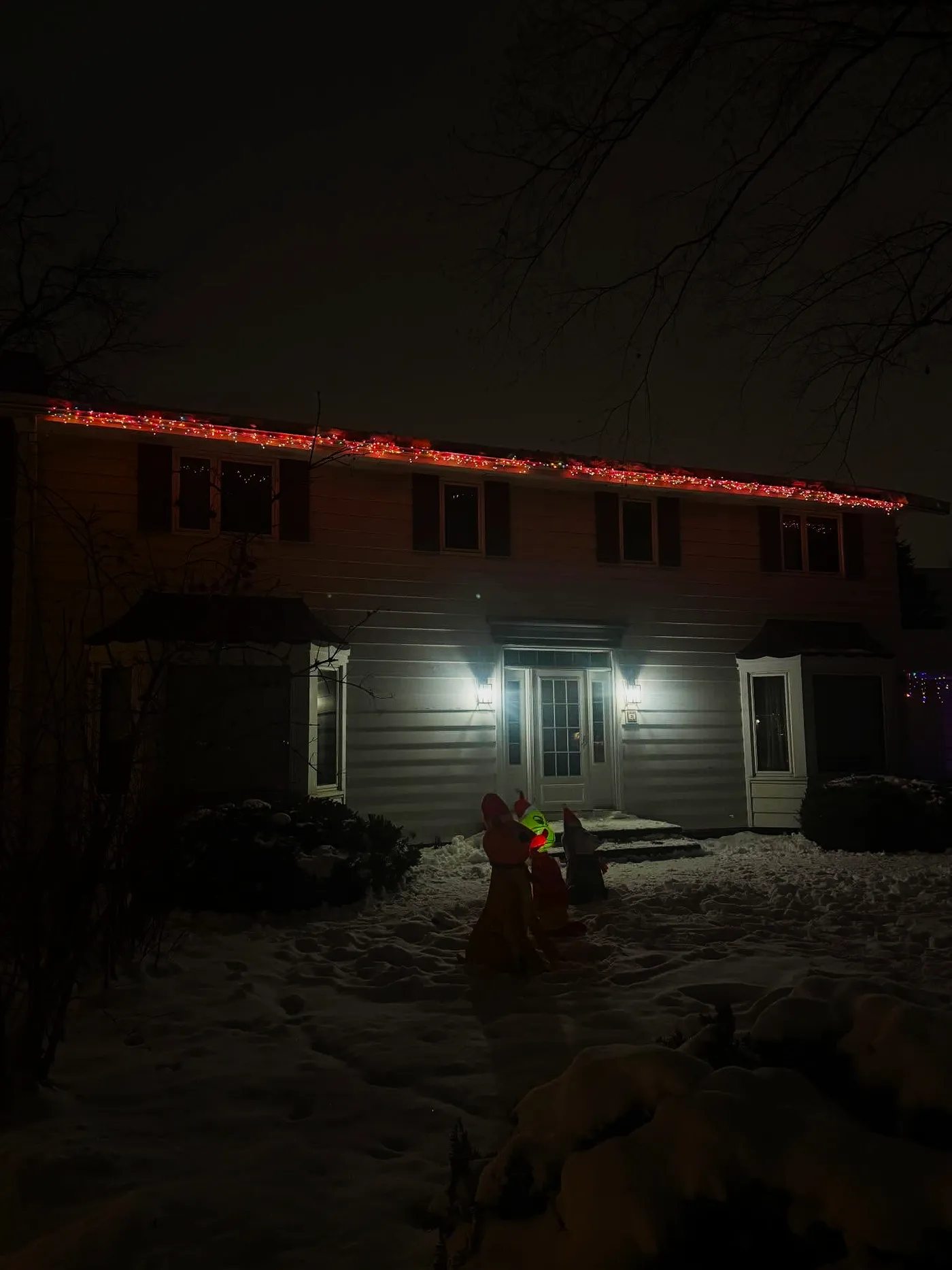 Red and multicolor Christmas lights tracing a snowy Minnesota roofline at night